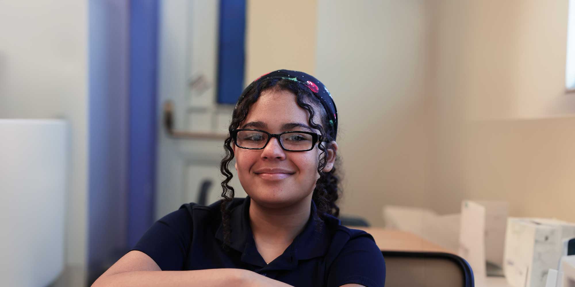 Smiling student with glasses and a patterned headband.