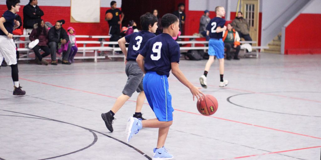 Students playing in a basketball game.